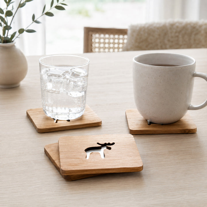 Houten glasonderzetters met uitgekerfde eland op een gedekte tafel
